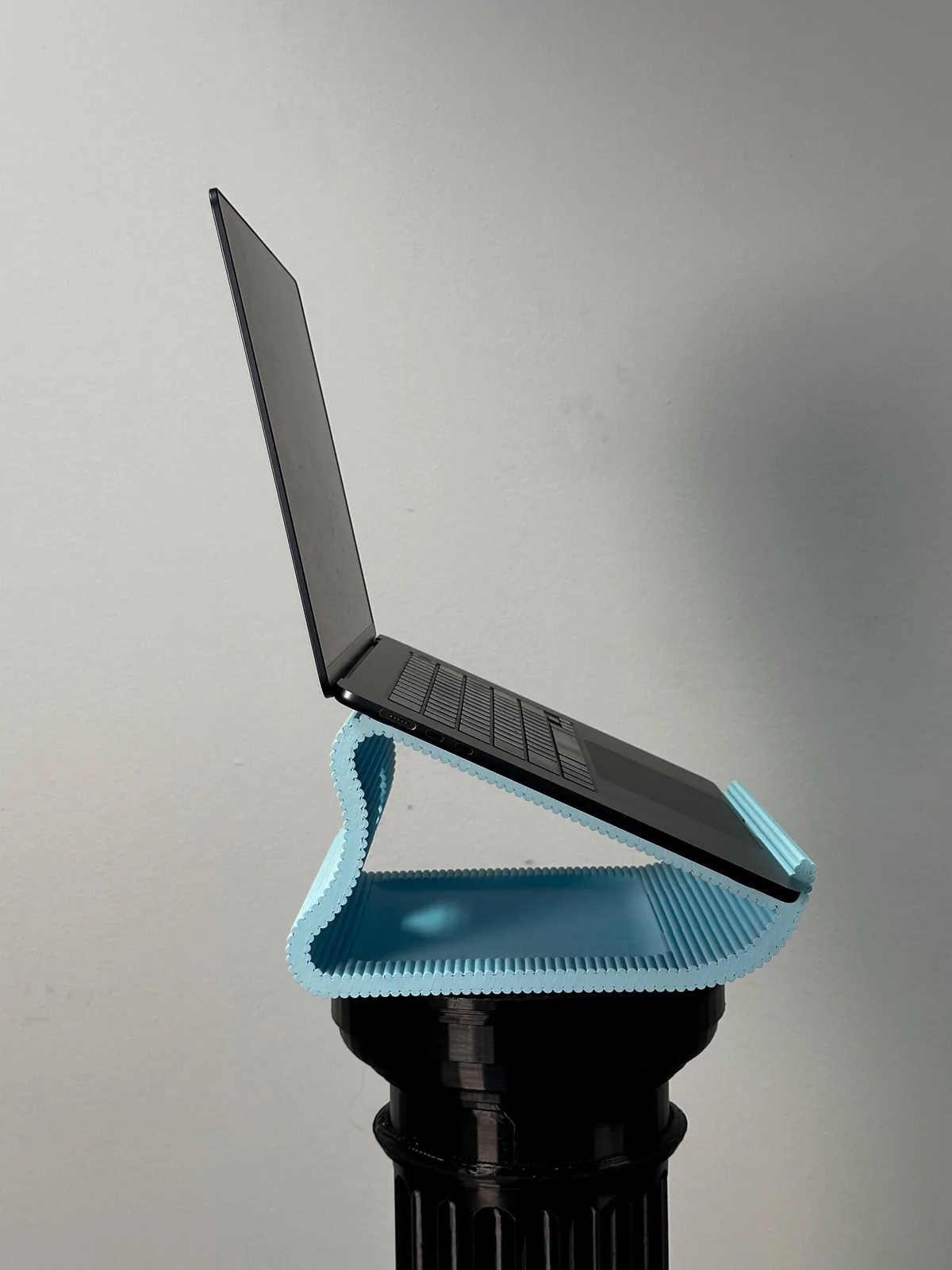The blue stand holding an open laptop, seen from the side