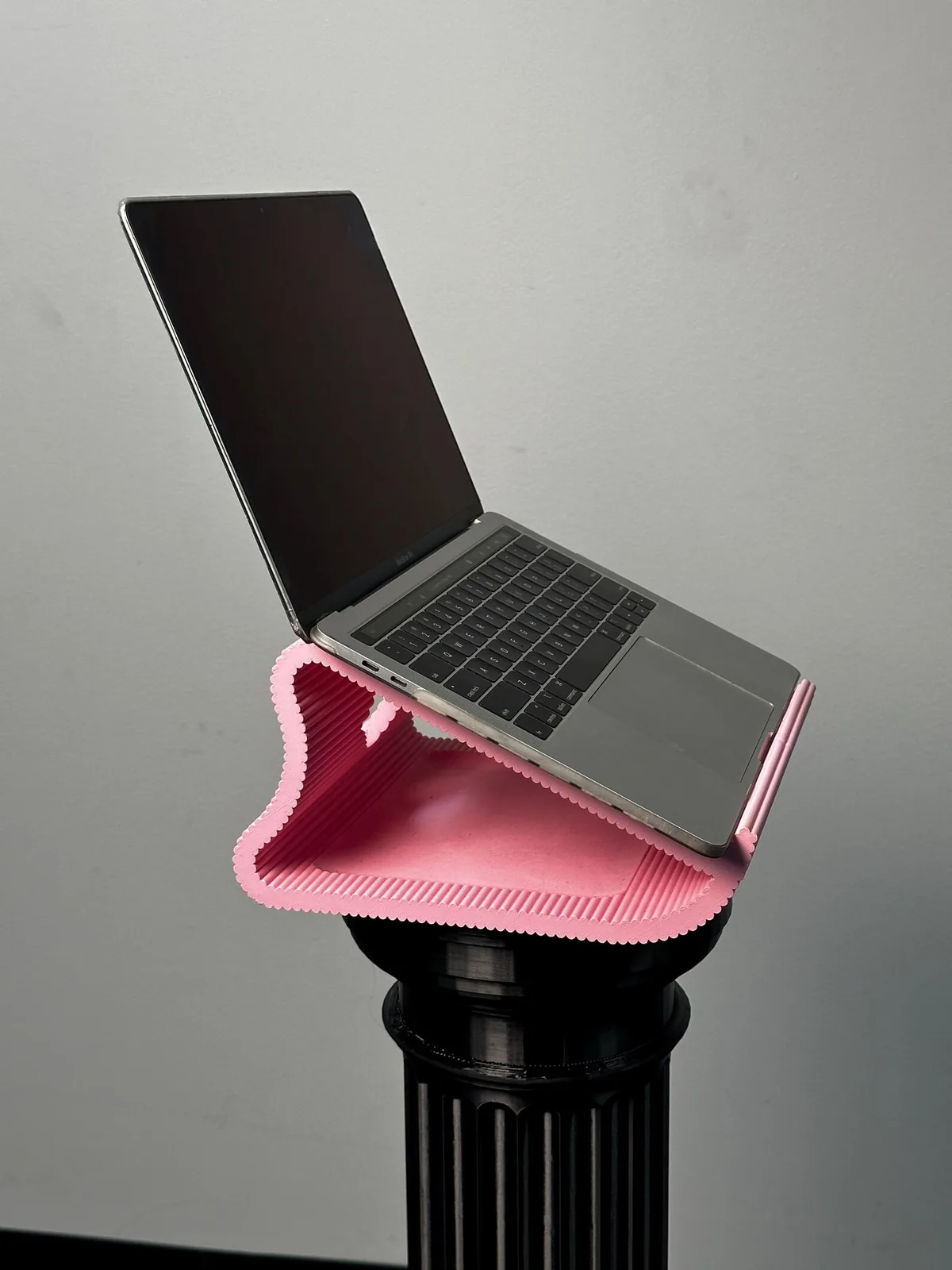 The pink stand holding an open laptop, seen from the side